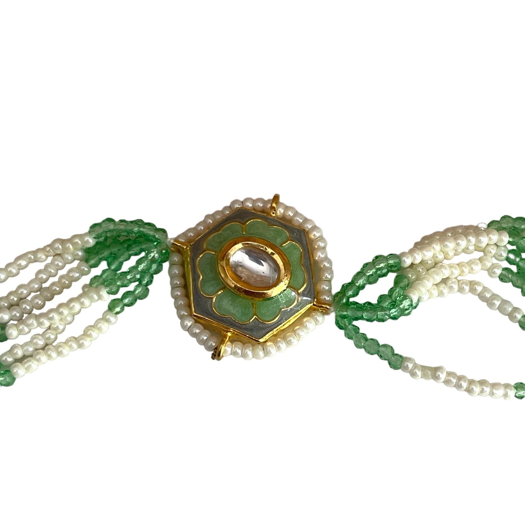 The Marguerite Bracelet features a bold hexagonal shape, surrounded by delicate Kundan stones and lustrous pearls. Elegant green enamel hand-painted to perfection brings a striking contrast to the bracelet, while green and white chains on either side create a harmonious balance of color and texture.