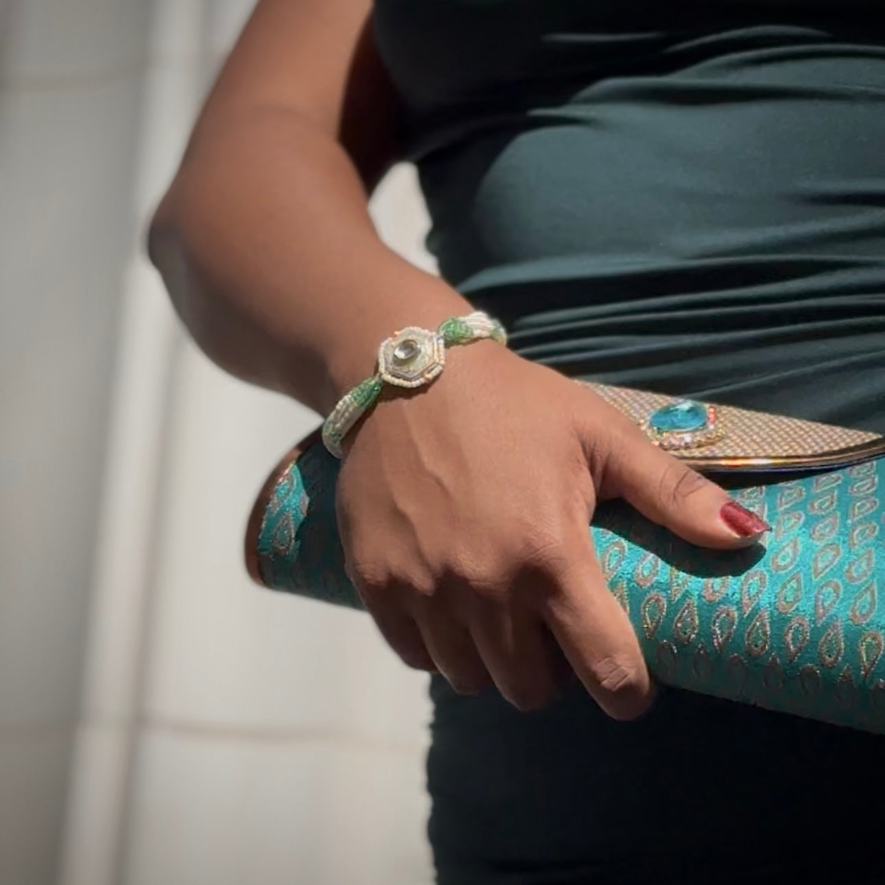 The Marguerite Bracelet features a bold hexagonal shape, surrounded by delicate Kundan stones and lustrous pearls. Elegant green enamel hand-painted to perfection brings a striking contrast to the bracelet, while green and white chains on either side create a harmonious balance of color and texture.