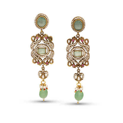 Ornate gold earrings with green gemstones on a white background