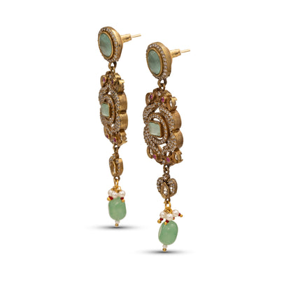 Gold earrings with green gemstones on a white background