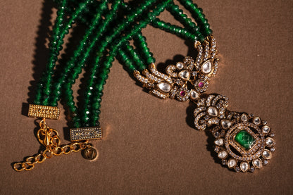 Green beaded bracelet with gold and silver jewelry on a brown background