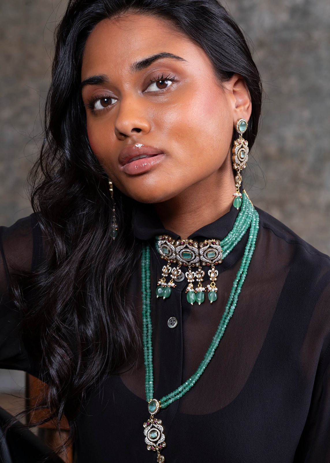 Woman wearing a green beaded necklace and earrings against a neutral background