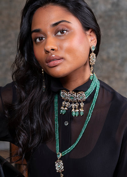 Woman wearing a green beaded necklace and earrings against a neutral background
