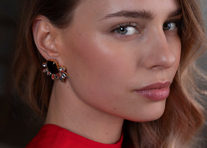Close-up of a woman wearing a black earring with a red background