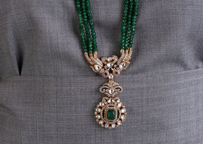 Decorative necklace with green beads and a pendant on a gray fabric background