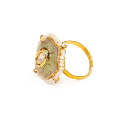 Gold ring with green gemstone and pearl-like beads on a white background