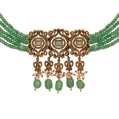 Ornate necklace with green beads and gold accents on a white background