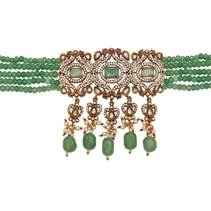 Green beaded necklace with gold and red accents on a white background