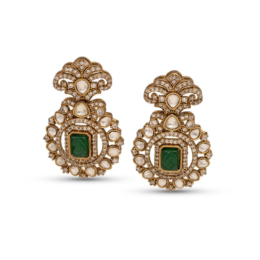Pair of ornate earrings with green gemstones and gold accents on a white background