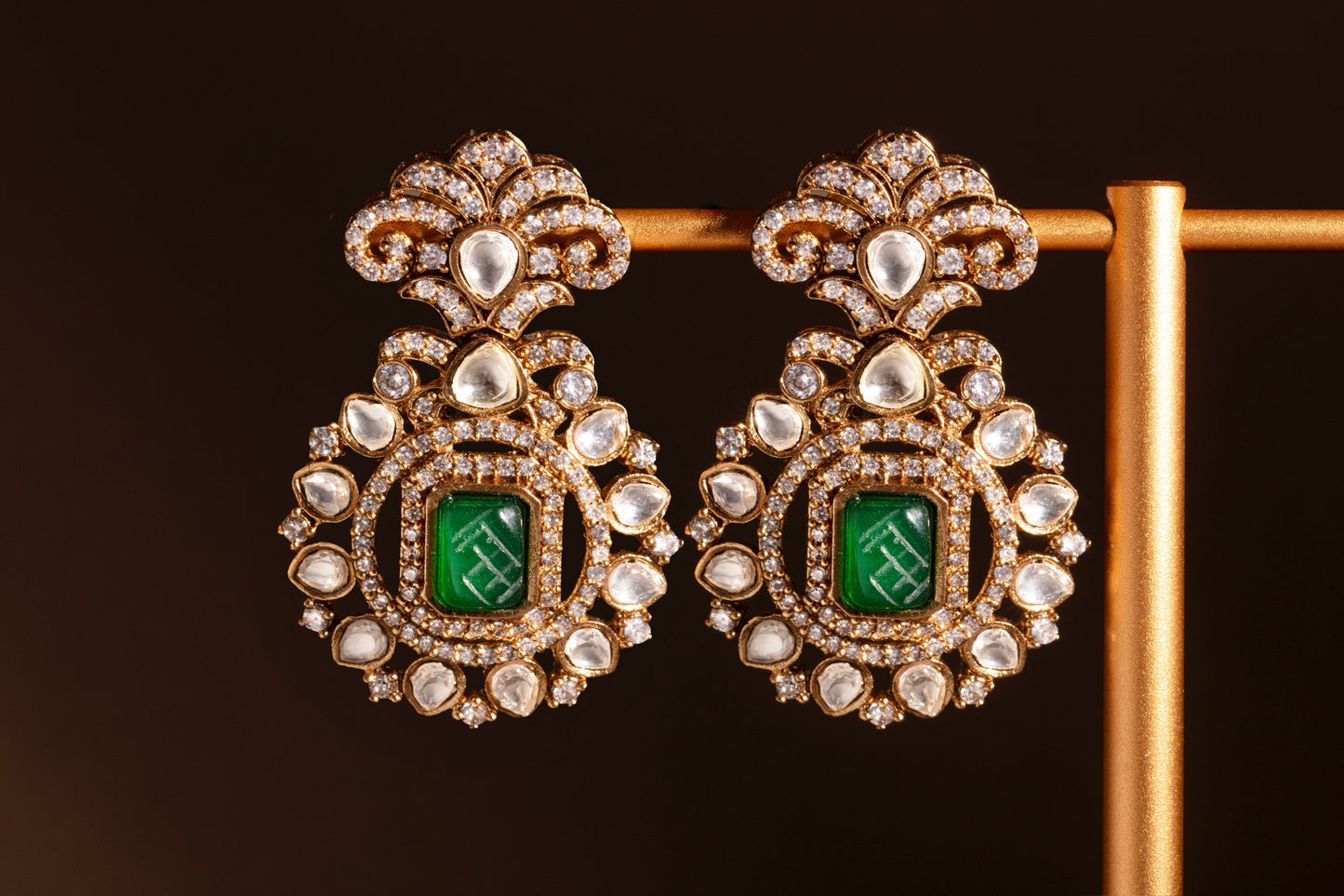 Ornate earrings with green gemstones on a dark background