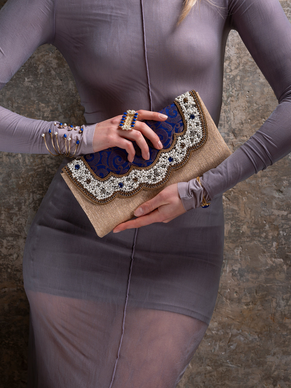 Person holding a beaded clutch with a textured background by Veronica Tharmalingam
