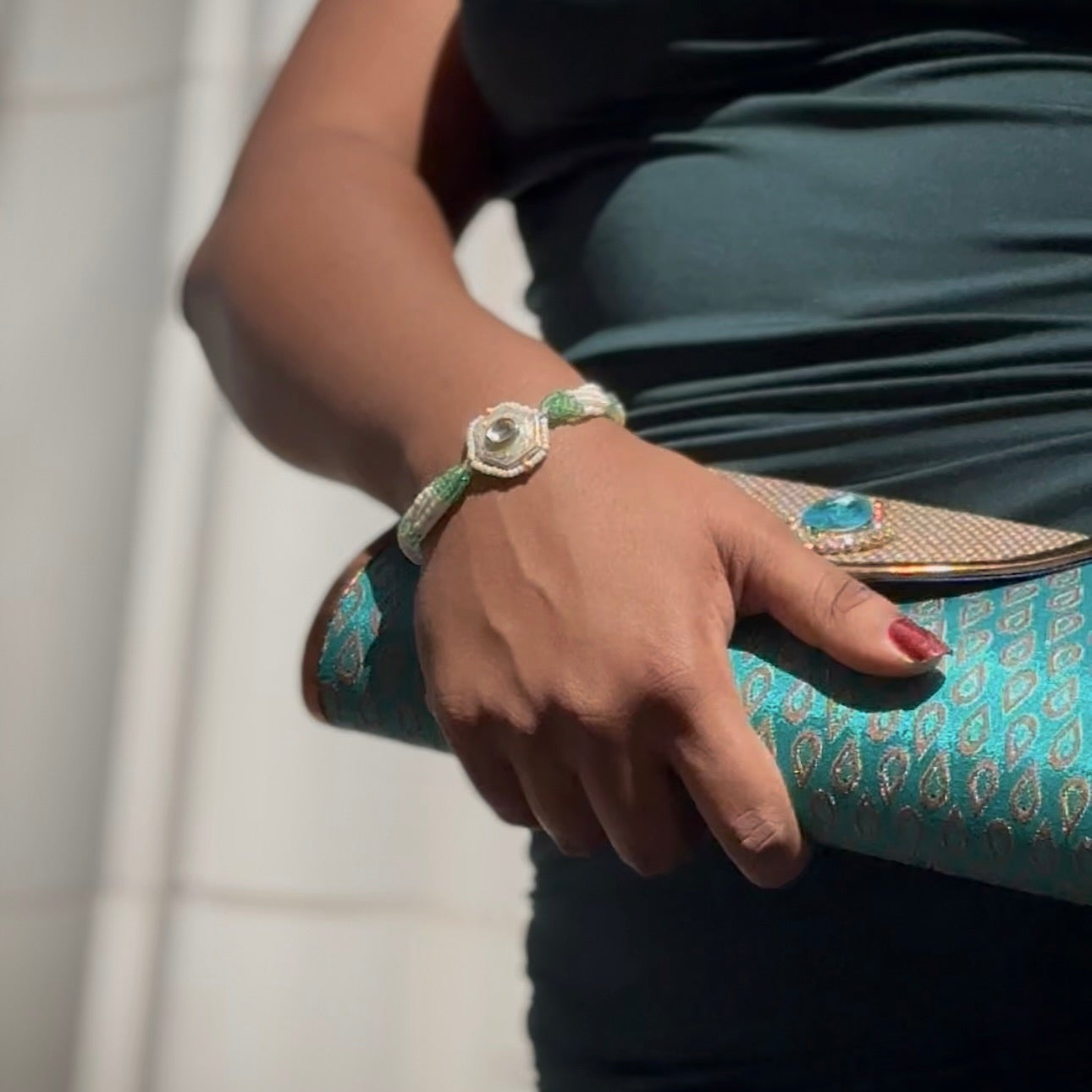 Person with bracelet with decorative elements against a neutral background