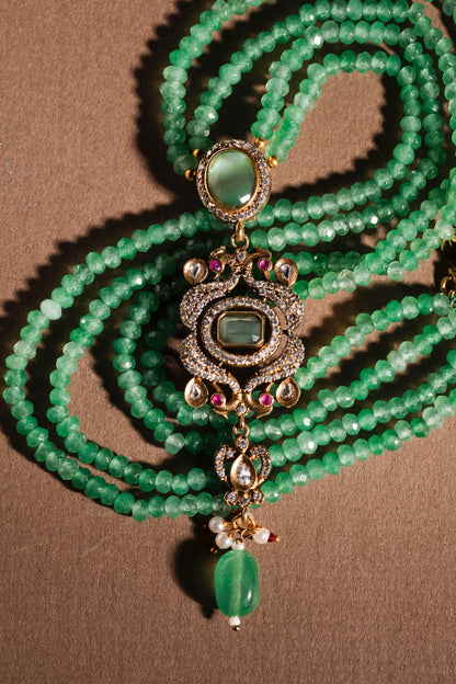 Green beaded necklace with decorative pendant on a brown background