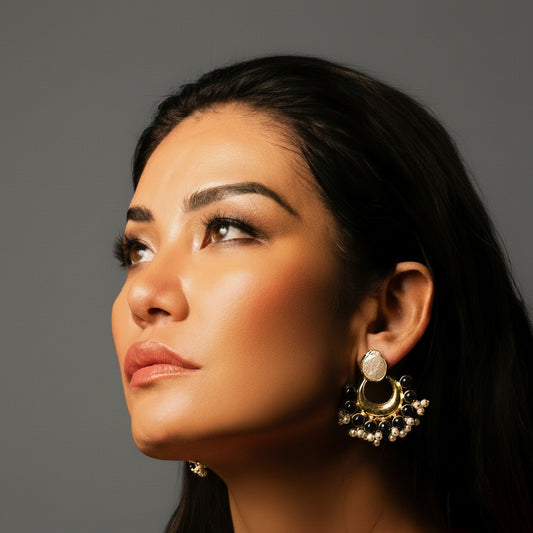Woman wearing large, ornate earrings against a neutral background
