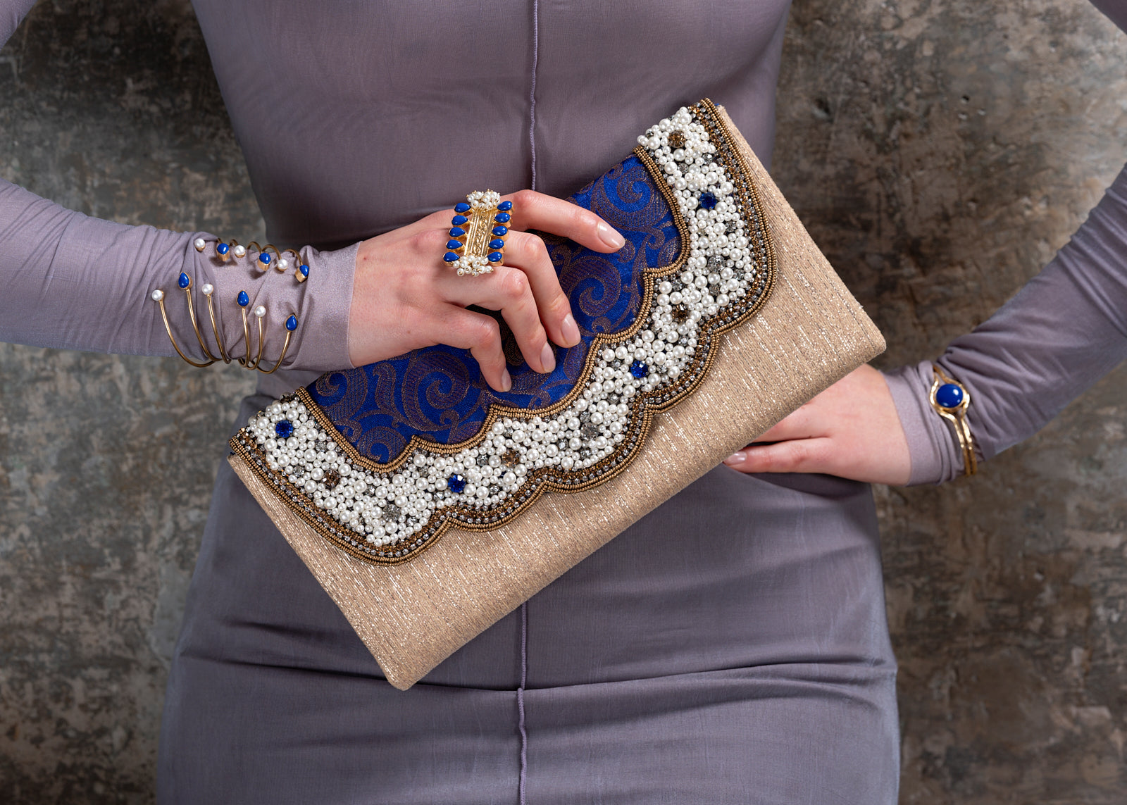 Person holding a decorative clutch with intricate patterns and embellishments.