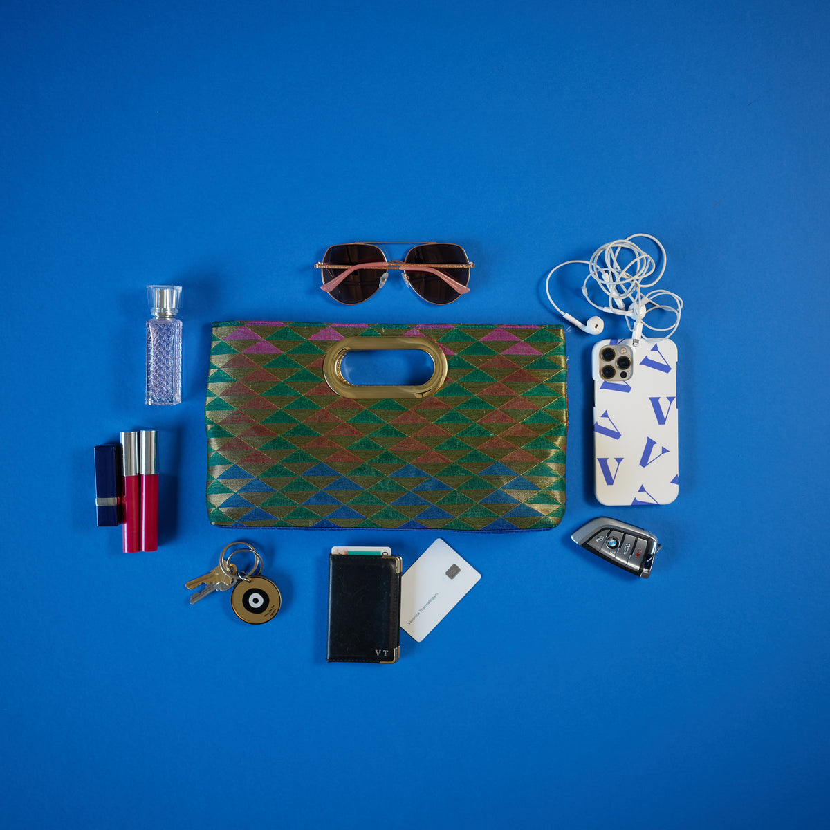 Everything that can fit into the Gaja Multi color mini tote with gold handle. Rani Collection as seen at NYFW 2021 Flying solo by Veronica Tharmalingam. Sunglasses, phone, headphones, perfume, lipstick and gloss,cards, keys and more